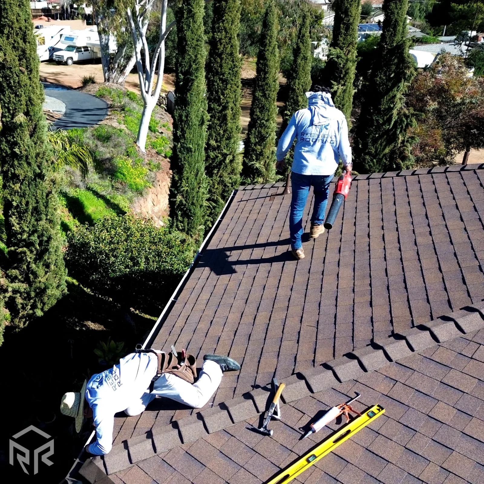 A Resilient Roofing field crew putting the finishing touches on a shingle roof