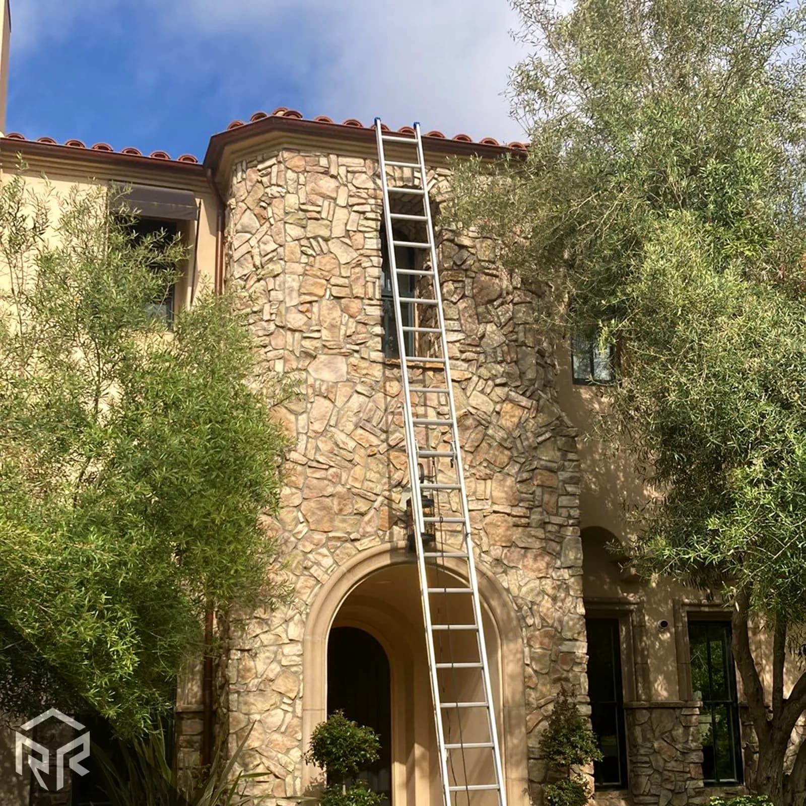 A photo of a tall ladder leaned against a house.
