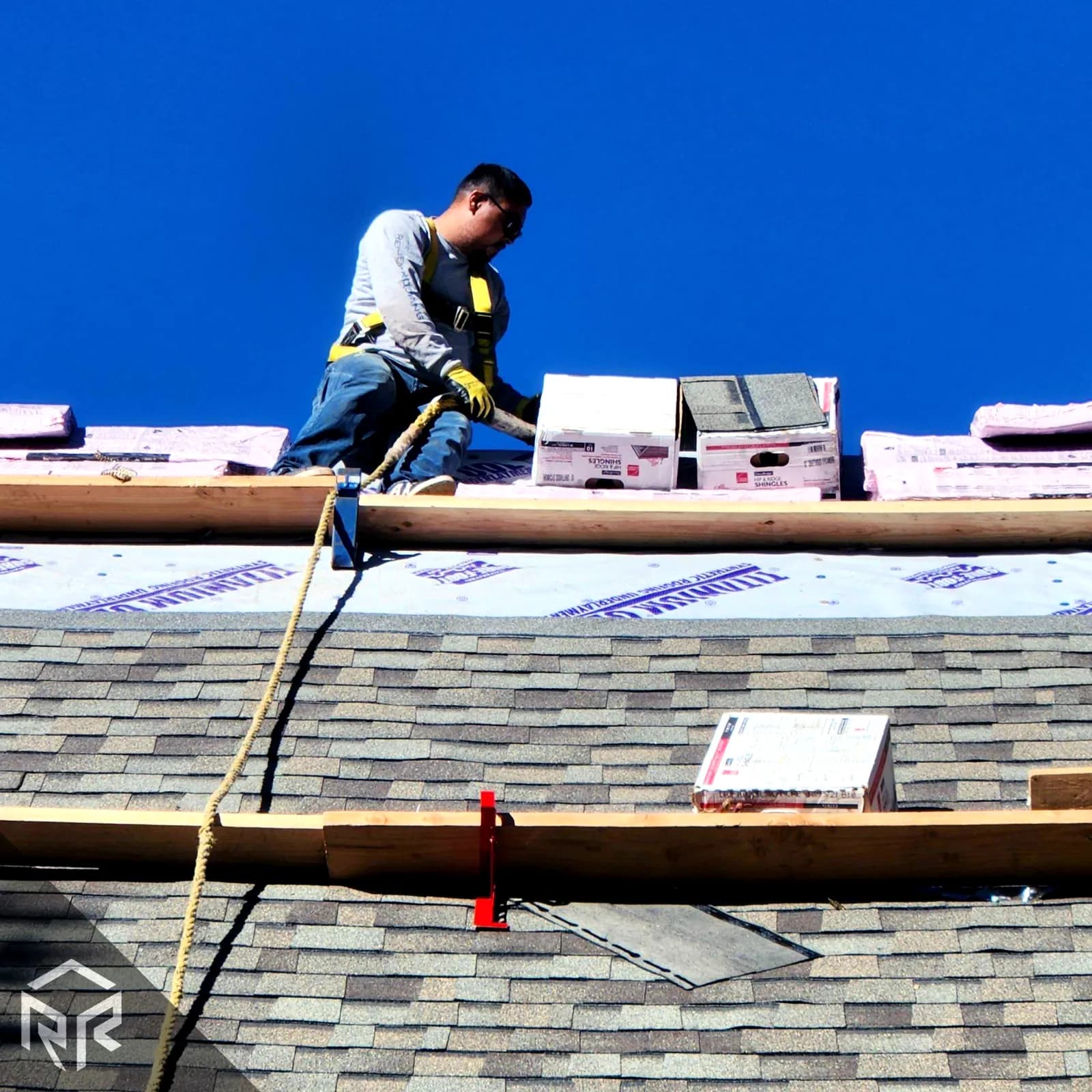 Resilient Roofing roofer working on installing Owens Corning shingles on a pitched roof.