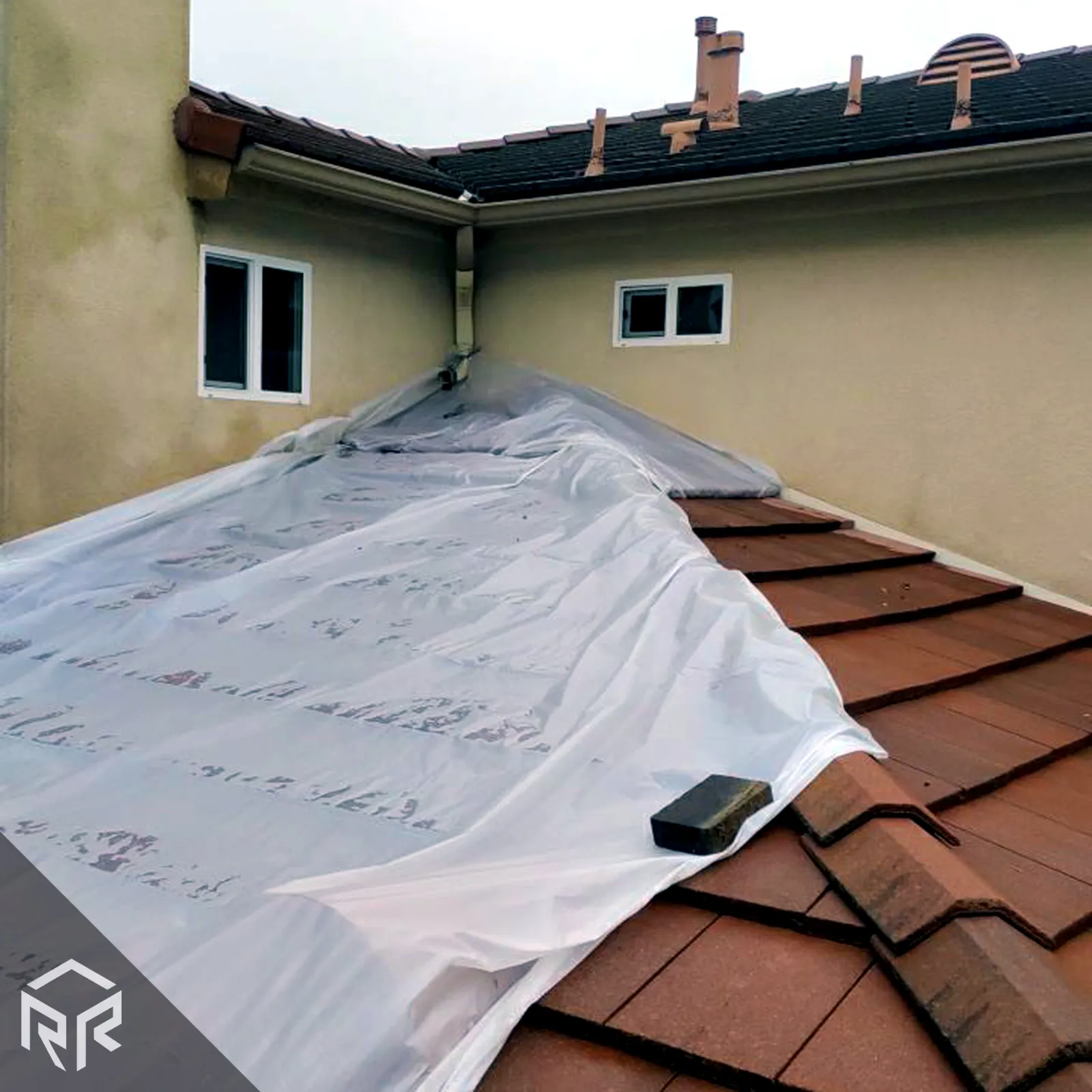 An emergency roofing tarp over a tile roof, installed by Resilient Roofing.