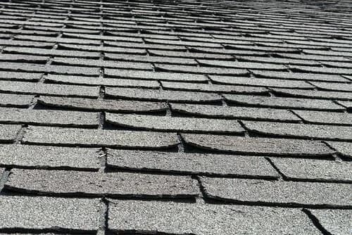 An aging asphalt shingle roof with curling, worn shingles — the kind of roof homeowners are often tempted to simply overlay.