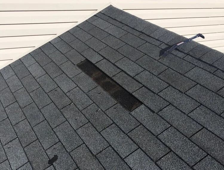 Asphalt shingles lifting and curling near a low spot on a roof.