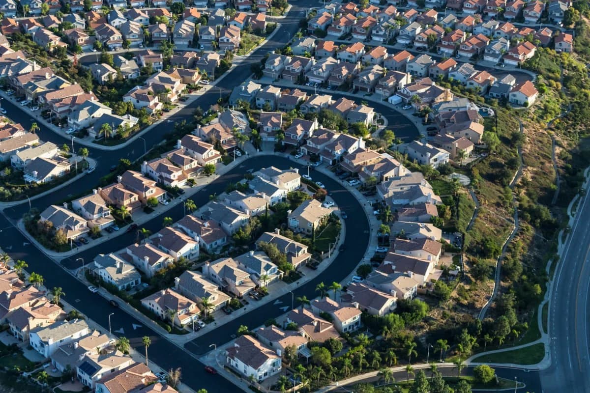 Aerial view of a hillside housing development with many tile and shingle roofs.