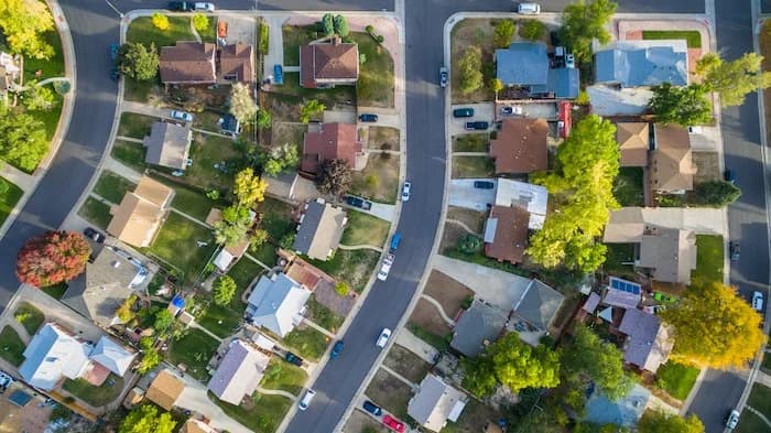 Aerial/drone view straight down over a residential subdivision with varied rooftops and driveways.