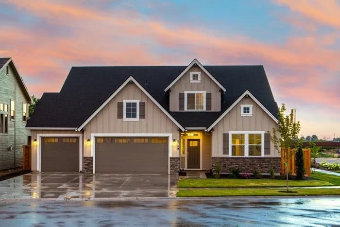 Craftsman-style suburban home with dark gabled roof at dusk after rain.