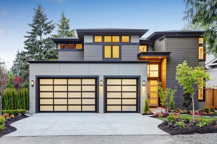 Modern two-story home exterior with glass-panel garage doors and a clean roofline.