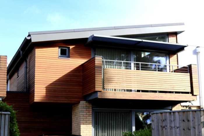 Contemporary wood-clad home with a balcony and angled metal roofline.