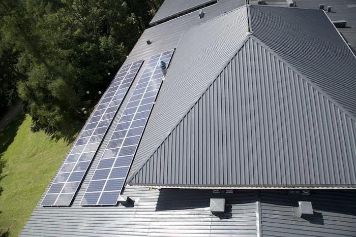 Solar panels mounted along the edge of a gray standing-seam metal roof.