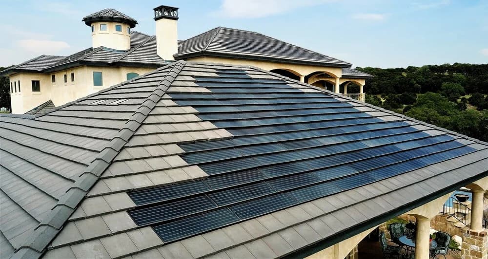 An aerial view of a stucco estate with a tile roof and integrated solar panels.