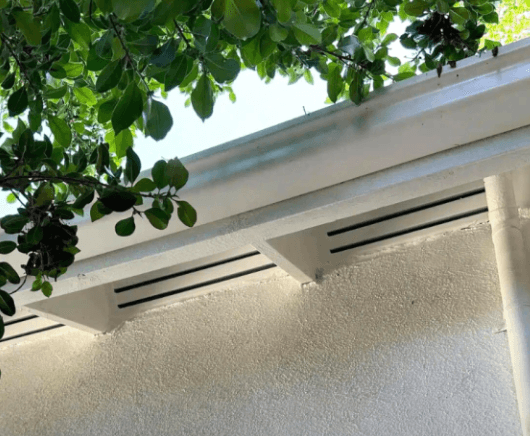 Two linear ember-resistant Brandguard soffit vents set into the white underside of a home's eave.