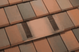 A low-profile O'Hagin ember-resistant vent blended into a multi-tone flat concrete tile roof.
