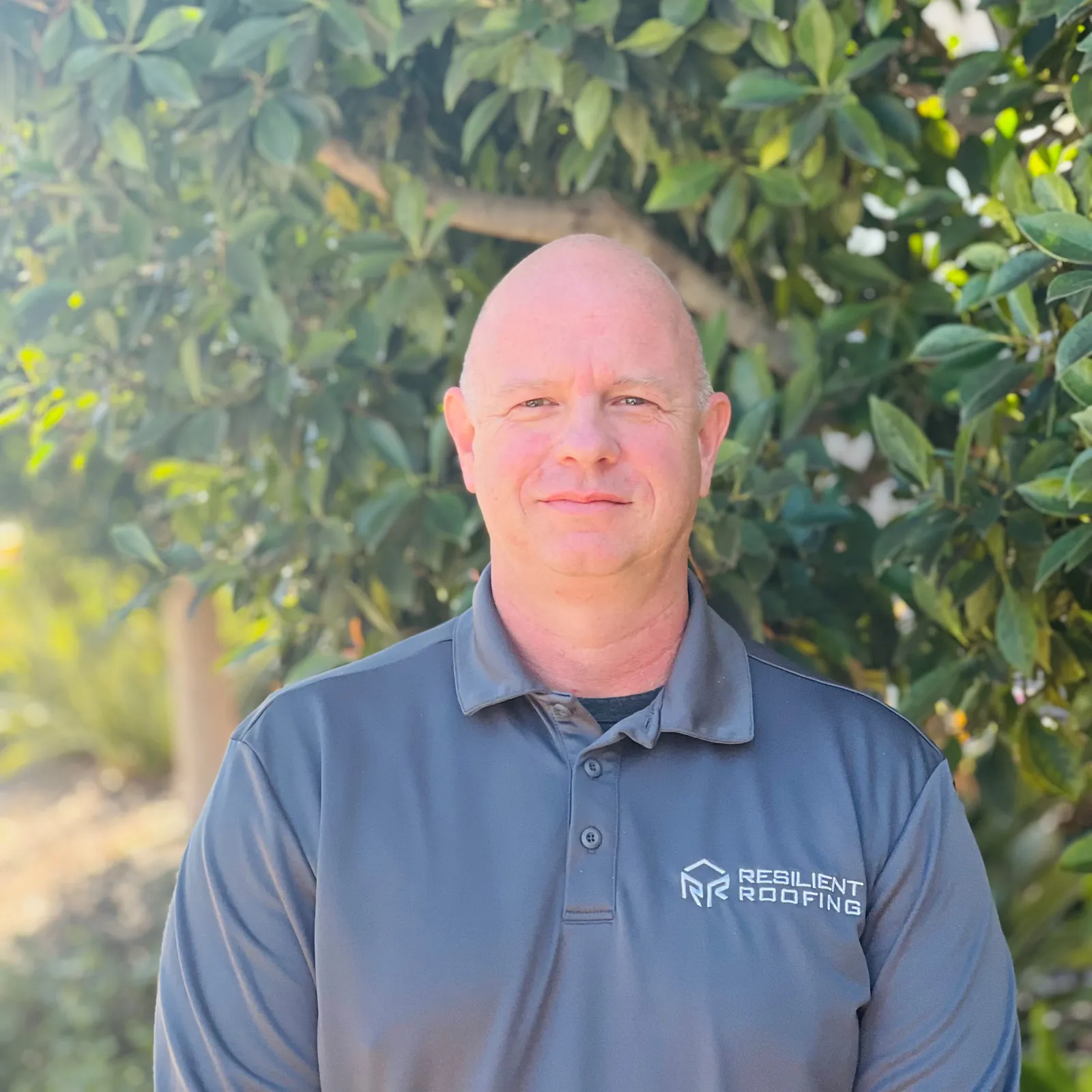 A man in a gray shirt with a company logo that says Resilient Roofing.